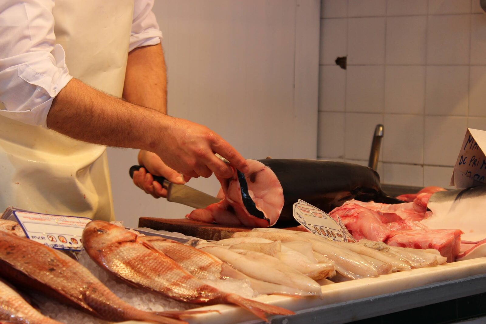 Cortando pescado fresco en el puesto del mercado